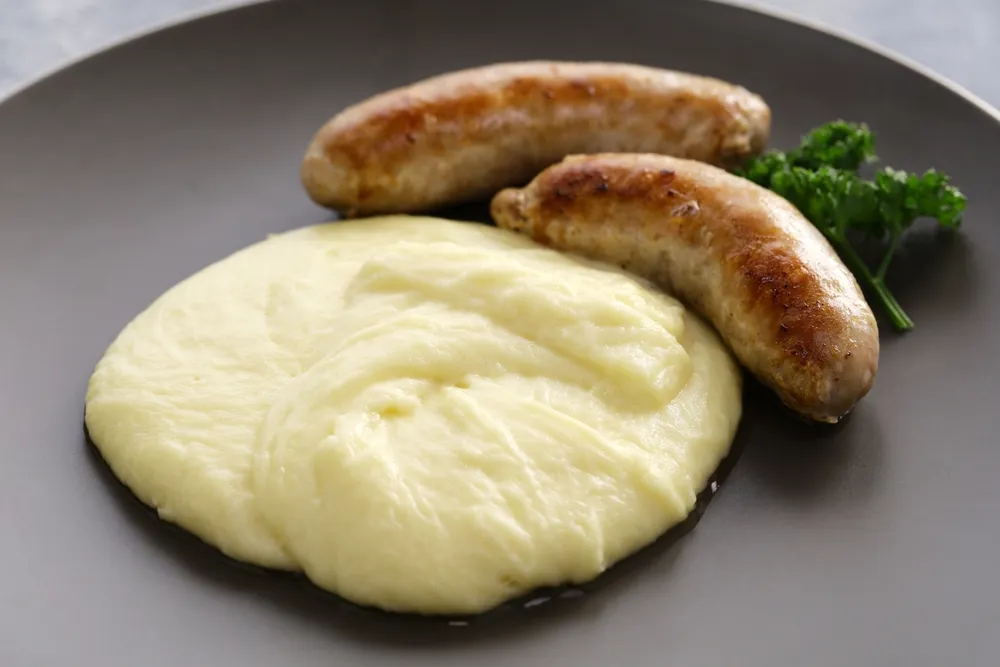 Assiette d'aligot onctueux de l'Aveyron avec saucisses dorées et persil