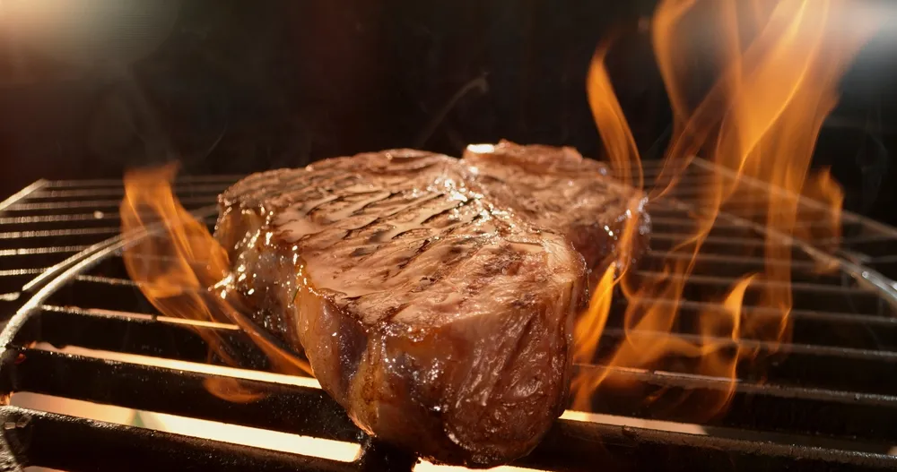 Côte de bœuf saisie sur brasero avec flammes vives