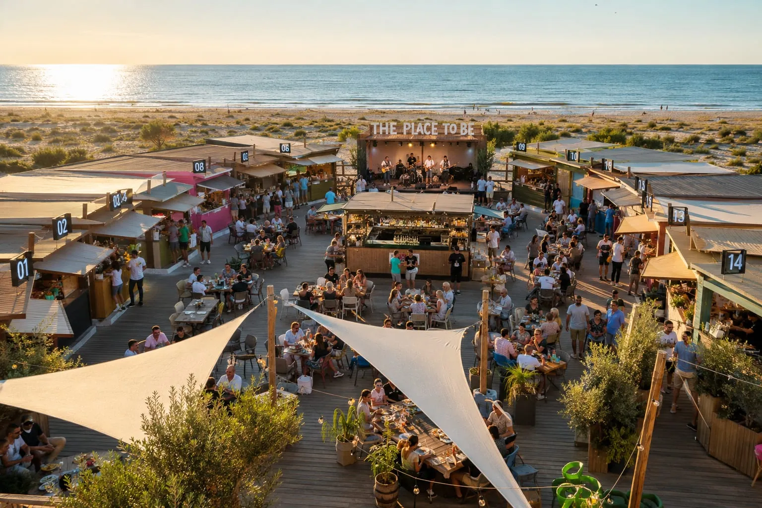 Vue panoramique des kiosques, du bar central et de la scène face à la mer au coucher du soleil